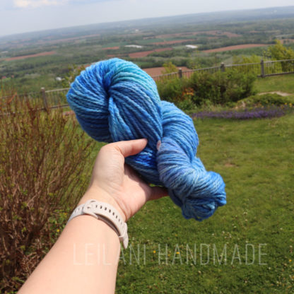 a hand holding a ball of blue yarn