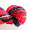 A close-up of a skein of yarn wound into a spiral. The yarn features bold stripes of red, dark blue, pink, and light tan. The background is white, making the vibrant colors of the yarn stand out clearly.