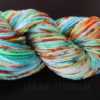A skein of hand-dyed yarn with vibrant colors including green, blue, orange, white, yellow, and flecks of red, twisted into a hank, is set against a dark background. The text “LEILANI HANDMADE” appears faintly at the bottom.
