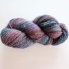 A skein of hand-spun yarn is displayed against a white background. The yarn features a blend of colors, including shades of gray, purple, teal, and red. The texture appears soft and slightly fluffy. The words "LEILANI HANDMADE" are faintly visible below.