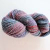 A twisted skein of multicolored yarn featuring shades of gray, blue, purple, and red. The strands are tightly spun together, creating a marled effect. The background is plain white and the words “LEILANI HANDMADE” appear faintly below the yarn.
