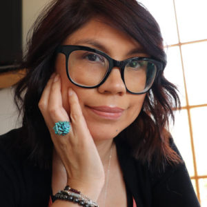 leilani seated with hand on face wearing handmade bracelets and turquoise ring