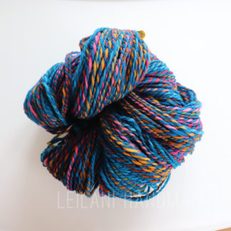 Close-up image of a skein of yarn featuring vibrant colors including blue, pink, yellow, and orange. Set against a plain white background.