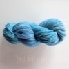 A neatly twisted skein of medium blue yarn rests on a white surface. The yarn has a soft, fluffy texture with slight color variations, ranging from lighter to darker blue tones. The text "LEILANI HANDMADE" is faintly visible at the bottom.