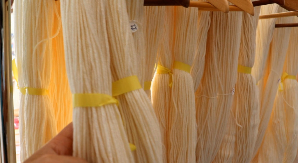 a rack of natural colored commercial yarn with yellow ties