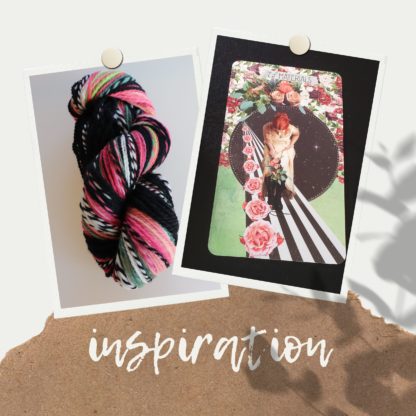 A skein of multicolored yarn next to an artistic card featuring a person on a striped path surrounded by roses. The word "inspiration" is written below on a textured surface.