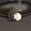 A silver necklace with a bee charm and a round pendant engraved with the letter “J” rests on a polished agate slice. The background is gray, and “LEILANI HANDMADE” is faintly visible at the bottom.